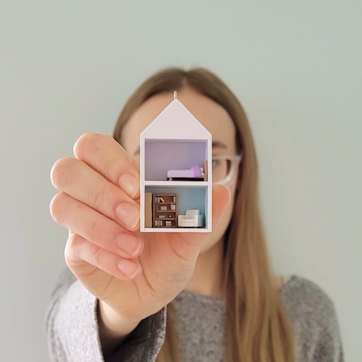 Gracie holding a micro-mini dollhouse up to the camera